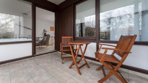 a porch with two wooden chairs and a table at Ferienwohnung Kellenhusen Ostsee in Kellenhusen