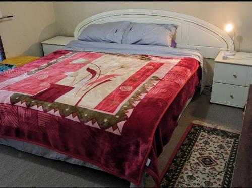 una camera con un letto con una coperta rossa di #BIDWILL GARDENS ON MIDDLETON# Private Room King Size Bed OR Open Lounge Room Floor Mattress SHARED Bathroom FREE Kitchen Essentials Fast NBN WIFI HDTV KAYO Sports Youtube FREE Laundry Facilities Transportation and Meal Services Available On Request a Sydney