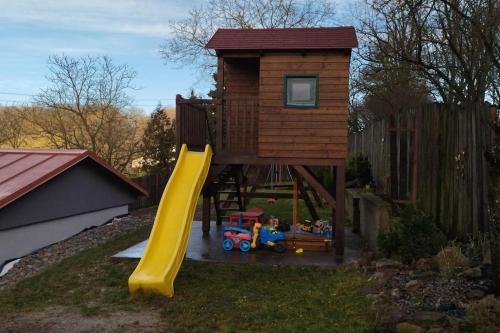 a play tower with a slide and a play house at Chalupa pod hradom Branč in Podbranč