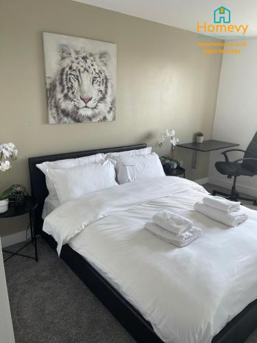 uma cama com lençóis brancos e uma imagem de um tigre em 1 Bedroom Apartment by Homevy Relocations Short Lets & Serviced Accommodation Leeds Dock - Stylish and Convenient em Leeds