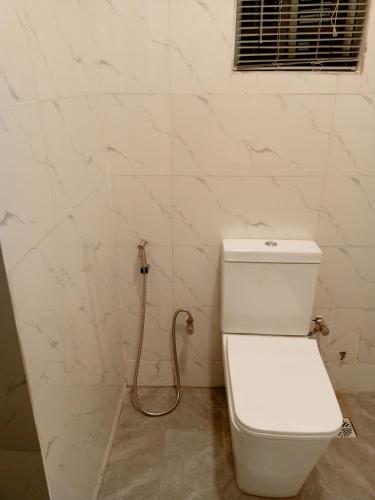 a white toilet in a bathroom with a hose at Inviting 2-Bed Apartment in Ifako-Ijaiye in Lagos