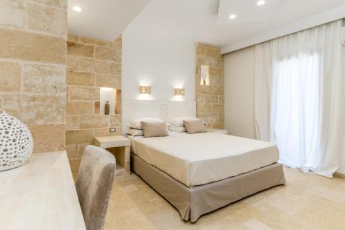 a bedroom with a large bed and a stone wall at Relais Porta del Sud in Ostuni