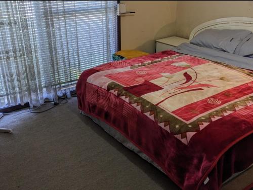 a bedroom with a bed with a red blanket on it at #BIDWILL GARDENS ON MIDDLETON# Private Room King Size Bed OR Open Lounge Room Floor Mattress SHARED Bathroom FREE Kitchen Essentials Fast NBN WIFI HDTV KAYO Sports Youtube FREE Laundry Facilities Transportation and Meal Services Available On Request in Sydney