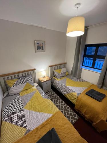 2 Betten in einem kleinen Zimmer mit Fenster in der Unterkunft Apartment 12, Sea Wharf in Westport