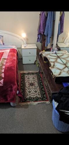 a bedroom with a bed and a table and a rug at BIDWILL GARDENS - 2 Rooms A Private Room with a King-Size Bed or Open Lounge Room Floor Mattress SHARED Bathroom FREE Kitchen Essentials FREE Laundry Facilities Fast NBN WIFI HDTV NETFLIX, YOUTUBE, KAYO Meal and Transport Service Available in Sydney