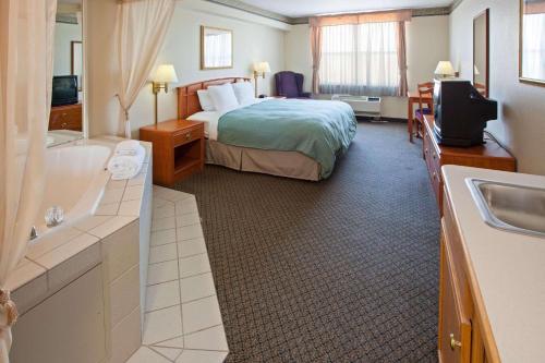 Country Inn & Suites by Radisson, Lansing, MI في لانسينغ: غرفه فندقيه بسرير وحمام