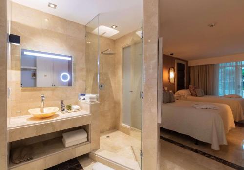 a bathroom with a sink and a shower and a bed at Hotel El Panama by Faranda Grand, a member of Radisson Individuals in Panama City