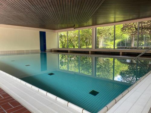 an indoor swimming pool with a large window and a poolasteryasteryasteryasteryastery at Skyline Appartement mit Pool and Netflix in Kronberg im Taunus