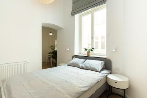 a white bedroom with a large bed with a window at The Bank Poznan Apartments in Poznań