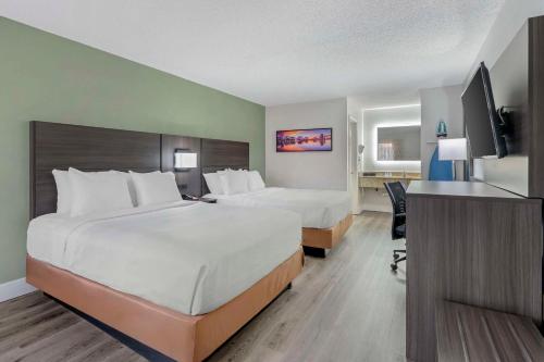 a hotel room with two beds and a desk at Quality Inn & Suites Orlando East - UCF Area in Orlando