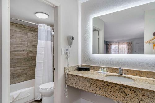 a bathroom with a sink and a toilet and a mirror at Quality Inn & Suites Orlando East - UCF Area in Orlando
