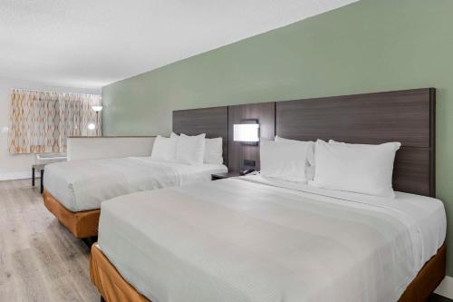 two beds in a hotel room with white pillows at Quality Inn & Suites Orlando East - UCF Area in Orlando