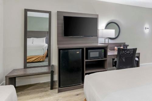 a hotel room with a bed and a desk with a television at Quality Inn & Suites Orlando East - UCF Area in Orlando