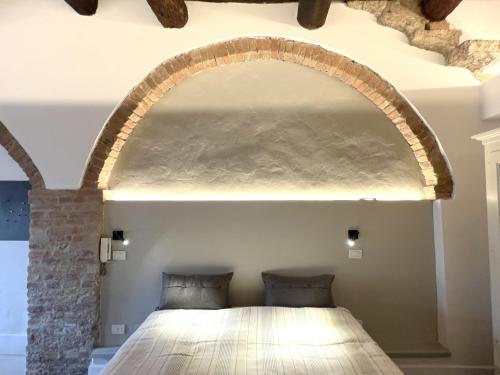 Bett in einem Zimmer mit einem Bogen darüber in der Unterkunft Fontebranda Nest in Siena