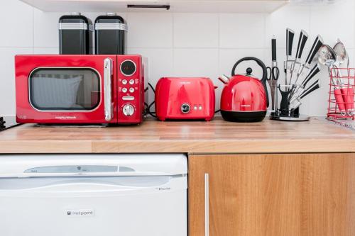 a red microwave sitting on top of a kitchen counter at Heaven in Cheam