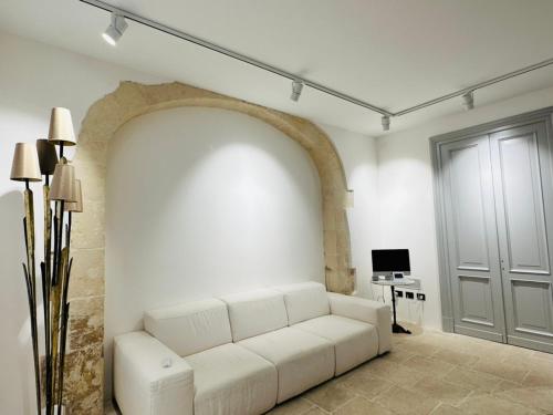 una sala de estar con un sofá blanco y un arco en La Dépendance Hotel, en Noto