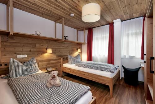 1 dormitorio con 2 camas y un osito de peluche en la cama en Landhaus Bachtelmühle, en Bolsterlang