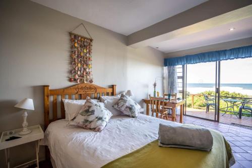 sypialnia z łóżkiem i widokiem na ocean w obiekcie The Spinning Reel Beach Cottages w mieście Port Alfred