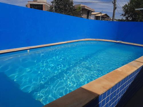a blue swimming pool with a blue wall at Suites Santa Amelia in Brotas