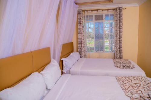 two beds in a room with a window at Calfie Resort Kisumu in Ahero