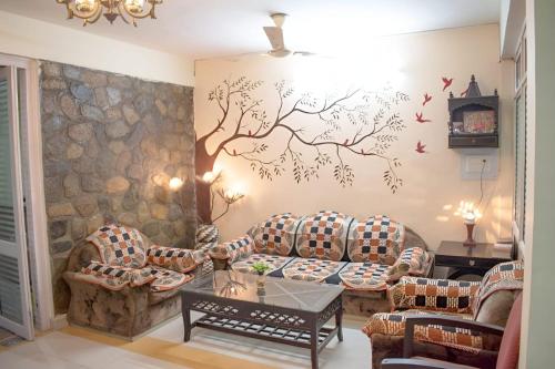 una sala de estar con sofás y un mural de árboles en la pared en Mannat Corbett Resort, en Rāmnagar