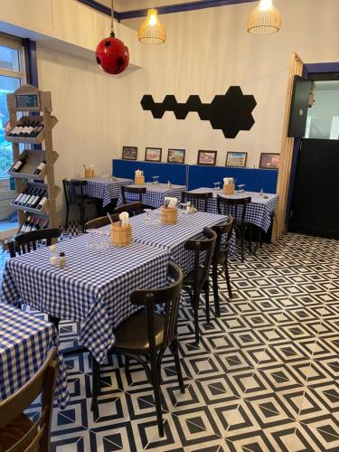 a dining room with tables and chairs and a bat sign on the wall at Hôtel L'Arbousier in Soulac-sur-Mer