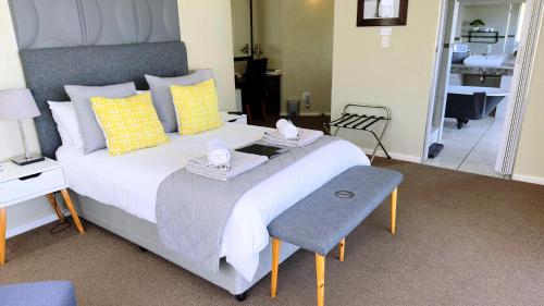 a bedroom with a large bed with yellow and gray pillows at Plattekloof Premium Lodge in Plattekloof