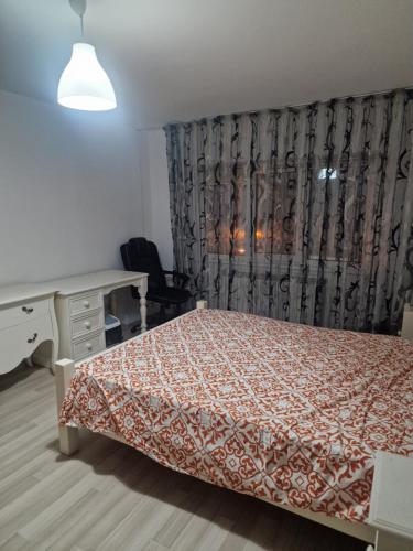a bedroom with a bed and a desk and a curtain at 2 bedrooms Apartment. in Galaţi