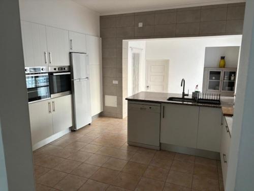 a kitchen with white cabinets and a tile floor at Villa GALVANA in Guia