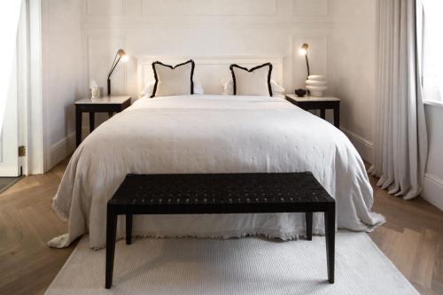 a white bedroom with a large bed with a black bench at NOAH House in Cape Town