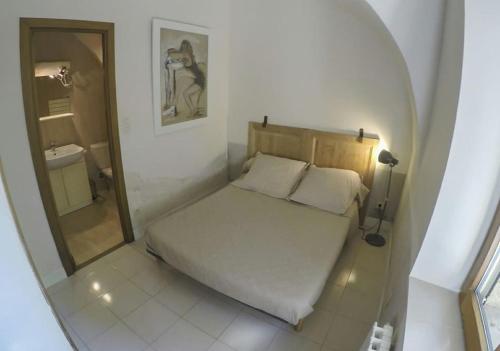 a small bedroom with a bed and a mirror at Appartement en pierre à proximité Lourmarin in Lauris