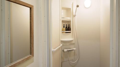 uma casa de banho com um chuveiro e um espelho. em almond hostel & cafe Shibuya em Tóquio