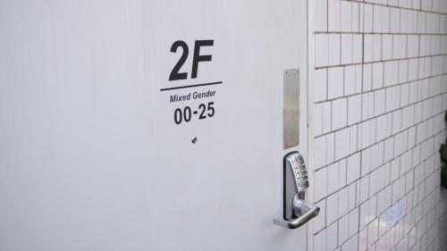 a white tiled bathroom door with a sign on it at almond hostel & cafe Shibuya in Tokyo