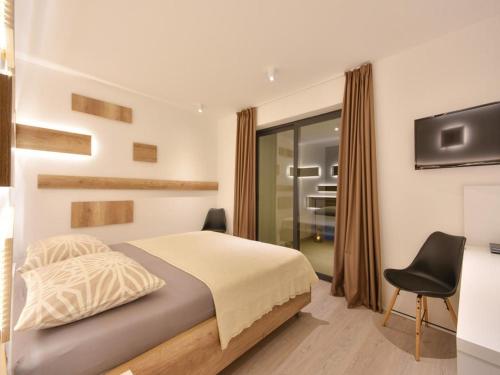 um quarto com uma cama, uma televisão e uma cadeira em Villa Formosa em Kaštela