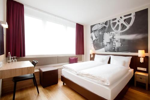 a hotel room with a bed and a desk at Vienna House Easy by Wyndham München in Munich