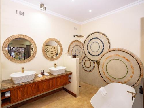 a bathroom with three sinks and mirrors on the wall at Insika lodge in Victoria Falls