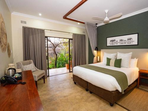 a bedroom with a bed and a chair and a window at Insika lodge in Victoria Falls