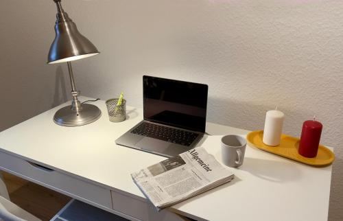 a laptop computer on a desk with a candle and a newspaper at Big flat with fresh renovation, free parking, SonyPS, Netflix in Duisburg