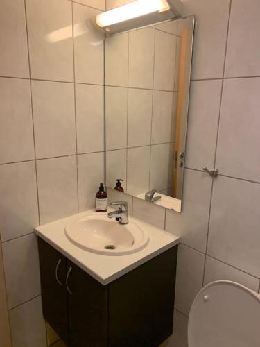 a bathroom with a sink and a mirror and a toilet at Svært sentral leiligheit in Sogndal