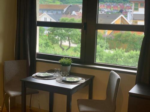 una mesa con platos y gafas delante de una ventana en Svært sentral leiligheit en Sogndal