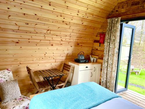 a bedroom with a bed and a table in a cabin at Alder Pod, Clay Bank Huts in Ingleby