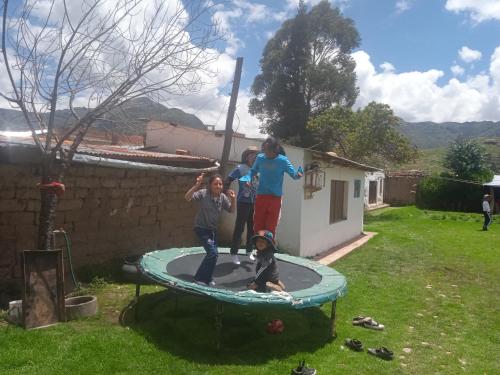 three children playing on a trampoline in a yard at Casa de campo hospedaje RyM in Sicuani