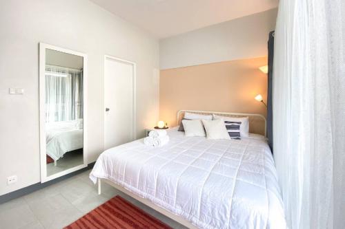 a bedroom with a large white bed and a mirror at Cozy 1br walk to BTS and Airport Rail Link Close to Malls T in Bangkok