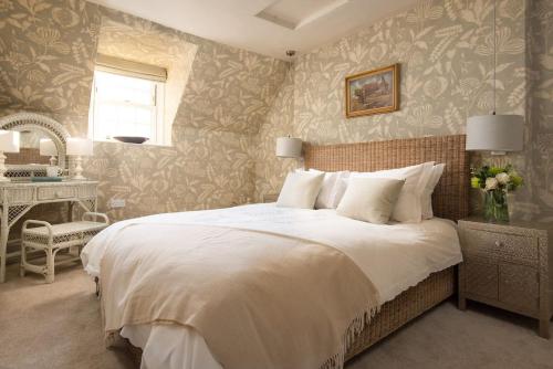 1 dormitorio con 1 cama blanca grande y escritorio en Bughtrig Cottage en Coldstream