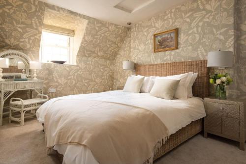 a bedroom with a large white bed and a desk at Bughtrig Cottage in Coldstream