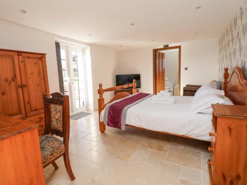 a bedroom with a bed and a chair and a mirror at The Shippon in Frodsham