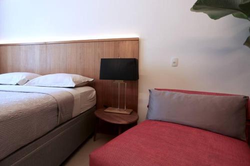 1 dormitorio con 1 cama y 1 sofá rojo pequeño en Art & Design Studio Ipanema, en Río de Janeiro