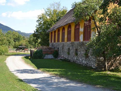 a stone building on a road next to a tree at Ferienwohnung Ottmanach Schlosshof in Pischeldorf