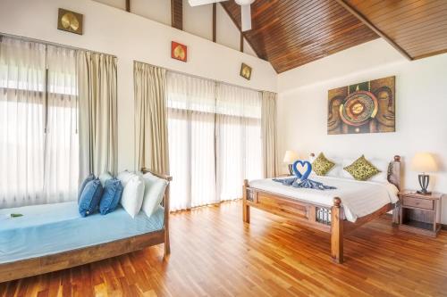 two beds in a room with wooden floors and windows at 3 Bedroom Villa Cara SDV042-By Samui Dream Villas in Mae Nam
