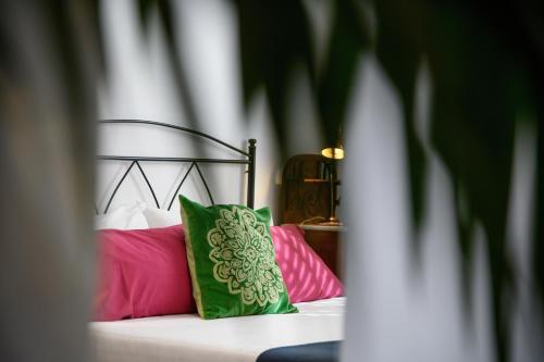 a bed with a green and pink pillow on it at Villa Golf Lanzarote in Costa Teguise